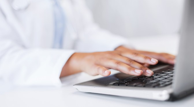 close up of female doctor hands typing on laptop computer
